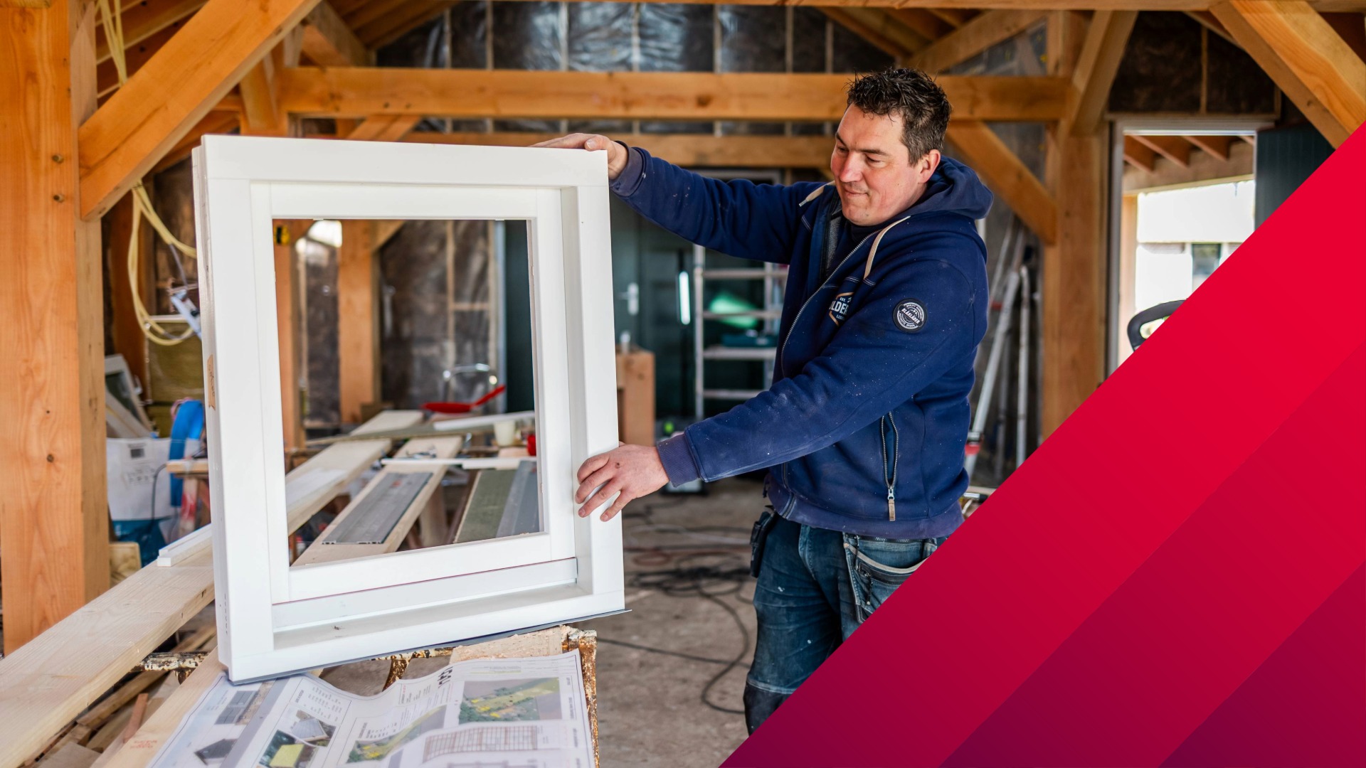 Ein Handwerker in einer Werkstatt hält und überprüft einen weißen Fensterrahmen während der Montage